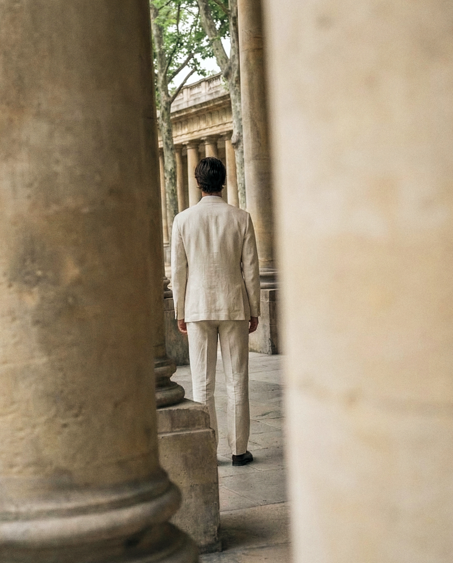 Ivory suit walking between columns